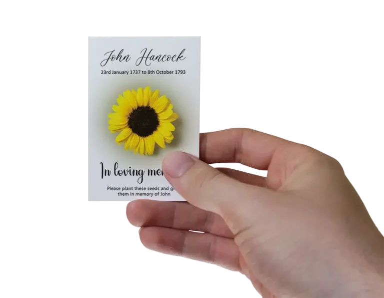 Hand holding a white envelope featuring a sunflower design containing funeral seeds.